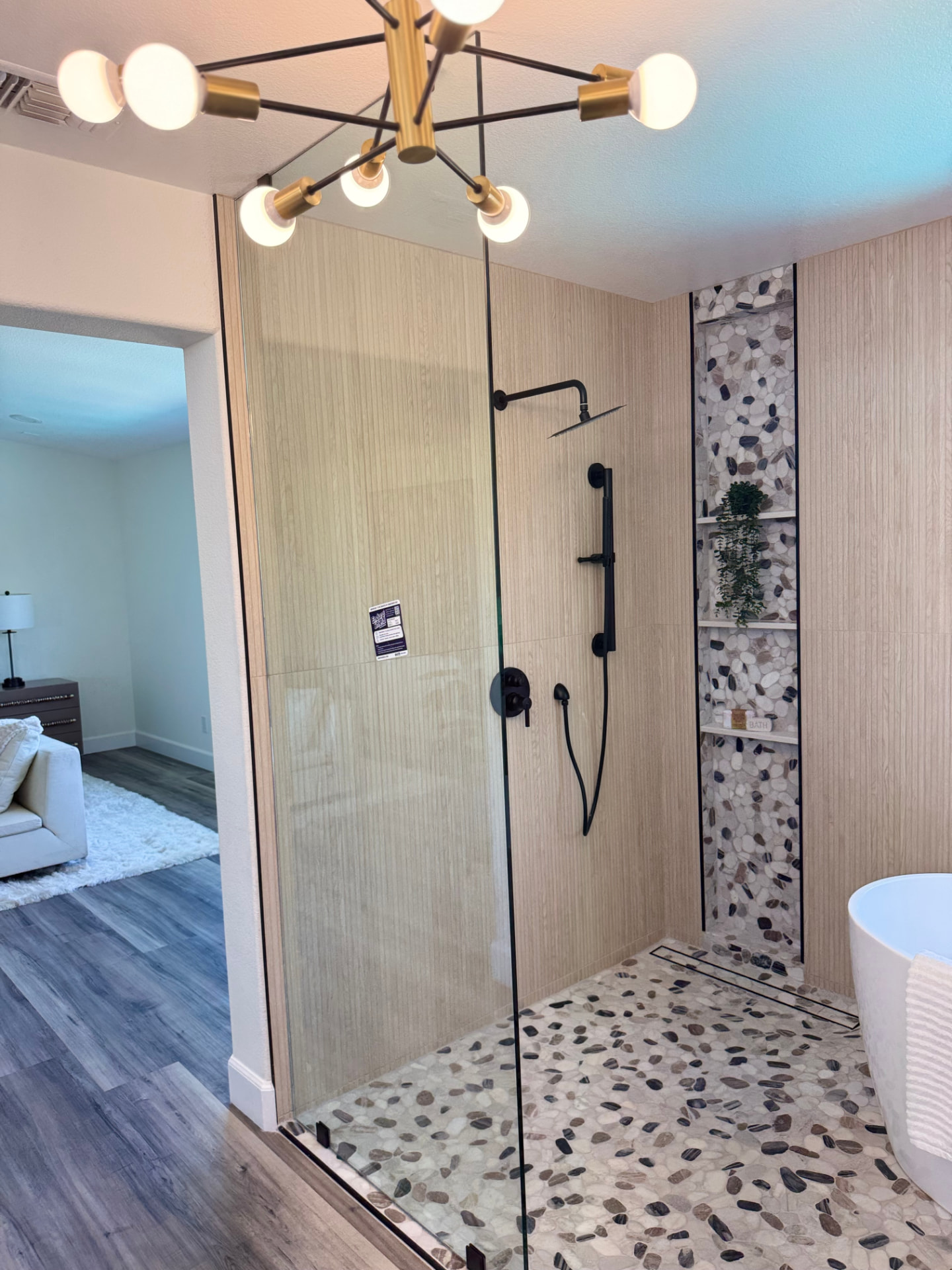 Walk-in glass shower with river-stone floor and matte black fixtures
