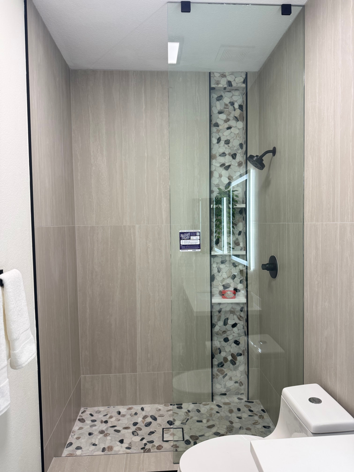 Tiled walk-in shower with stone accent niche and glass panel